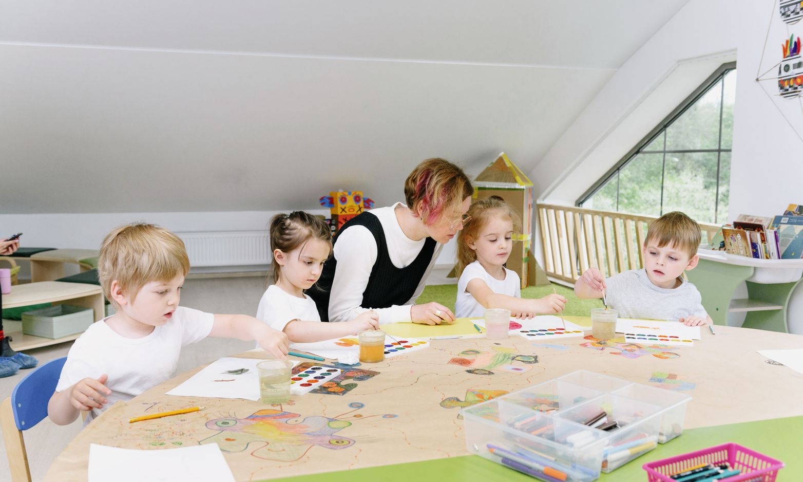 Young children painting with a teacher in a kindergarten classroom