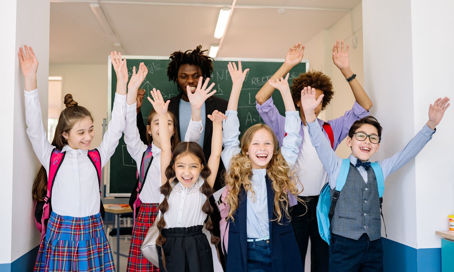 School children in uniform raising their hands in a classroom