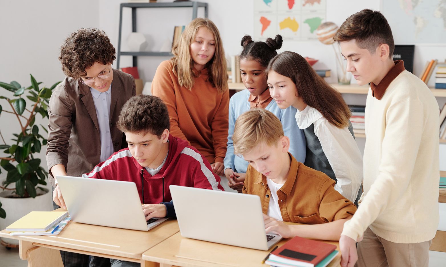 Group of students working together on laptops in a classroom